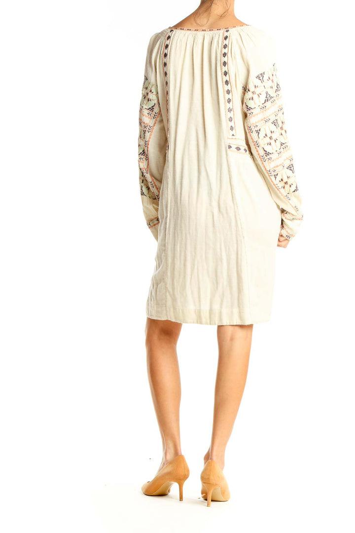 Back view of cream Free People mini dress showing embroidered sleeves and flowy silhouette