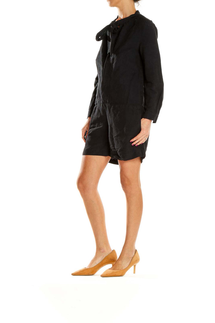 Front view of A.P.C. black long-sleeve romper with tie-neck detail