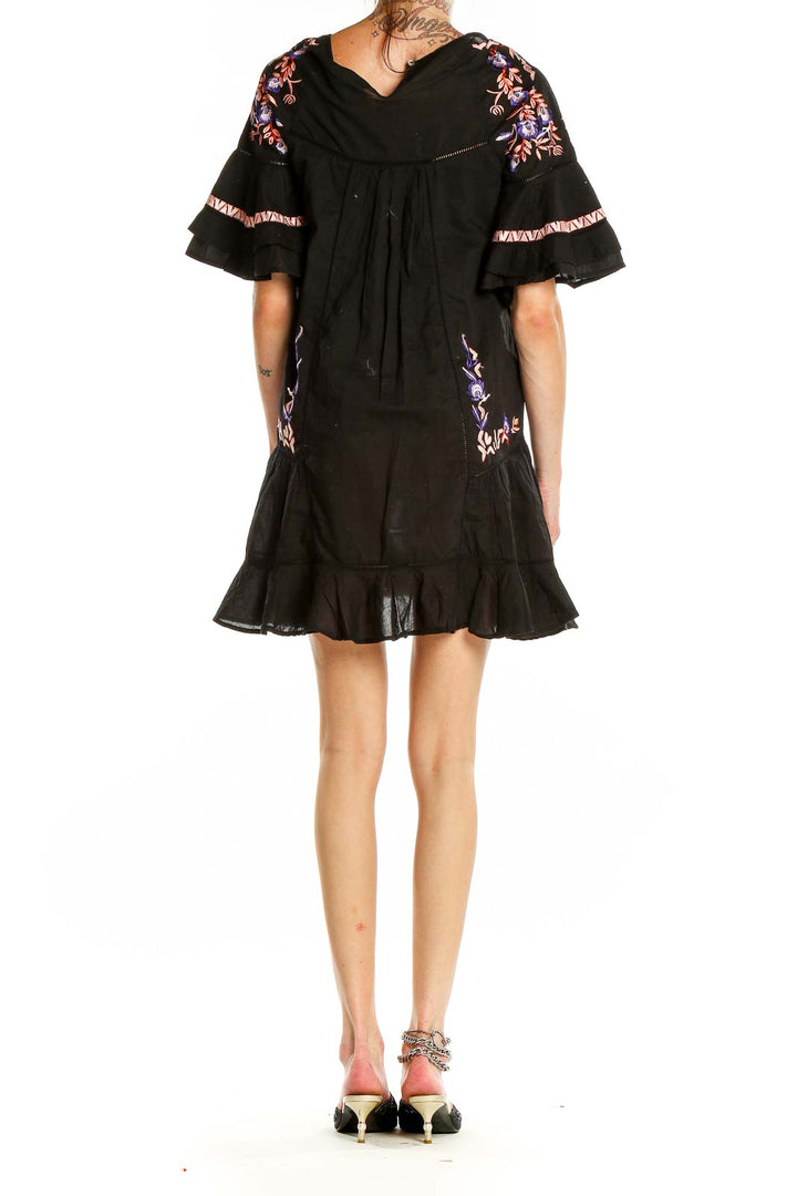 Back view of Free People black mini dress showing embroidery pattern and ruffle hem