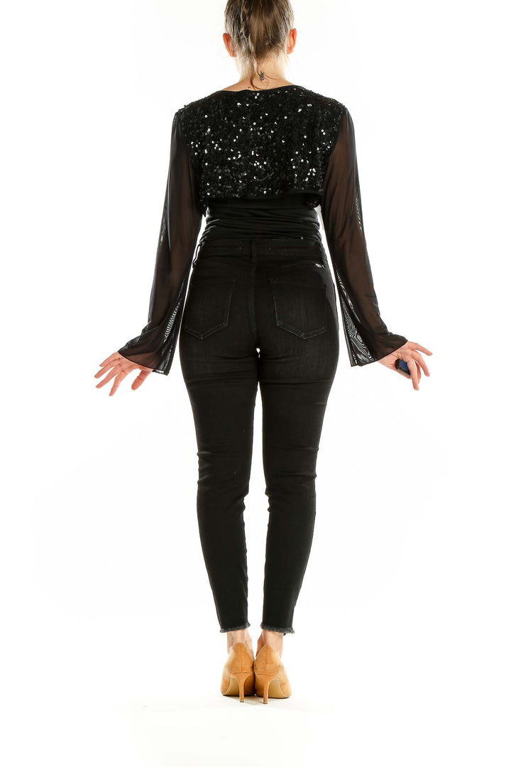 Back view of black sequined crop top with sheer sleeves