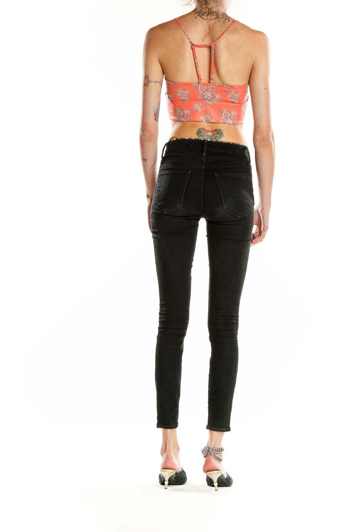 Side view of model wearing Anthropologie coral floral cropped camisole with black jeans