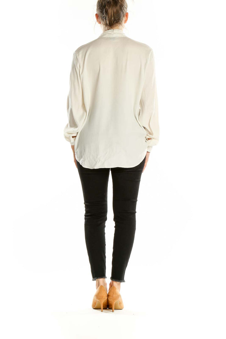 Back view of ivory Ann Taylor blouse on model with black pants