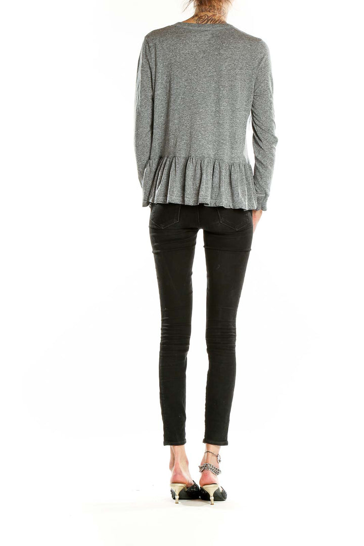 Back view of The Great gray peplum long sleeve top on model with black jeans