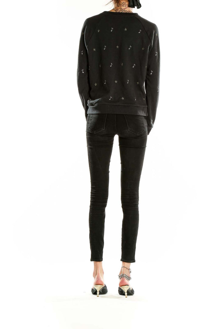 Side view of woman wearing Levi's black embellished sweatshirt with jeans