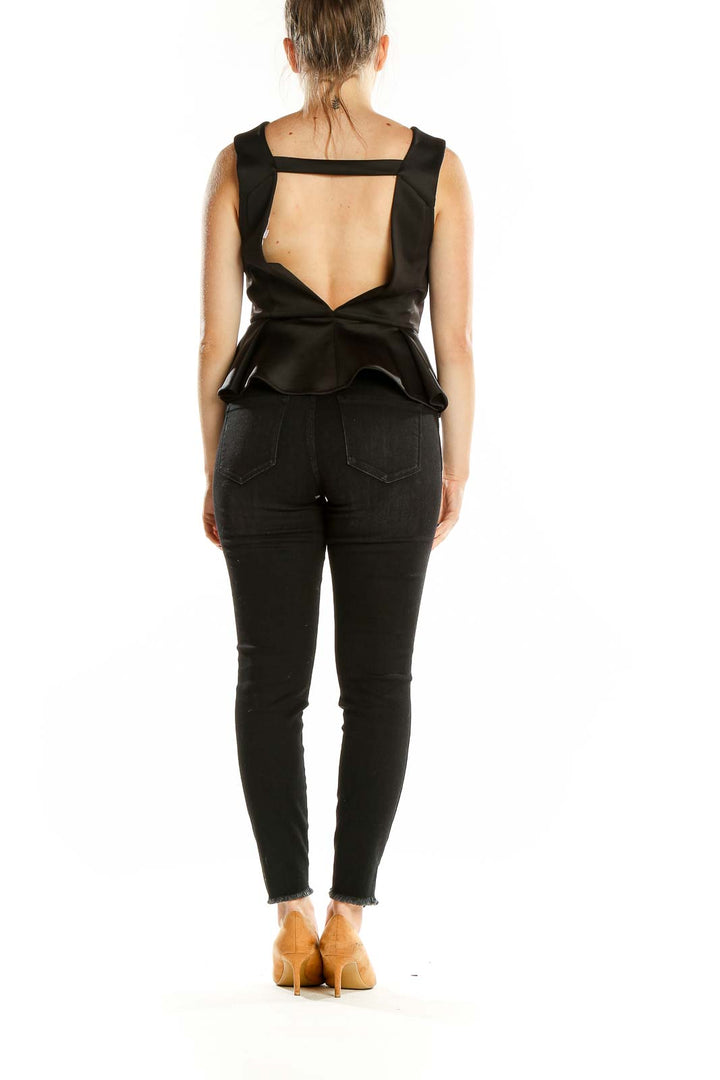 Back view of BCBGeneration black sleeveless peplum top with cutout design