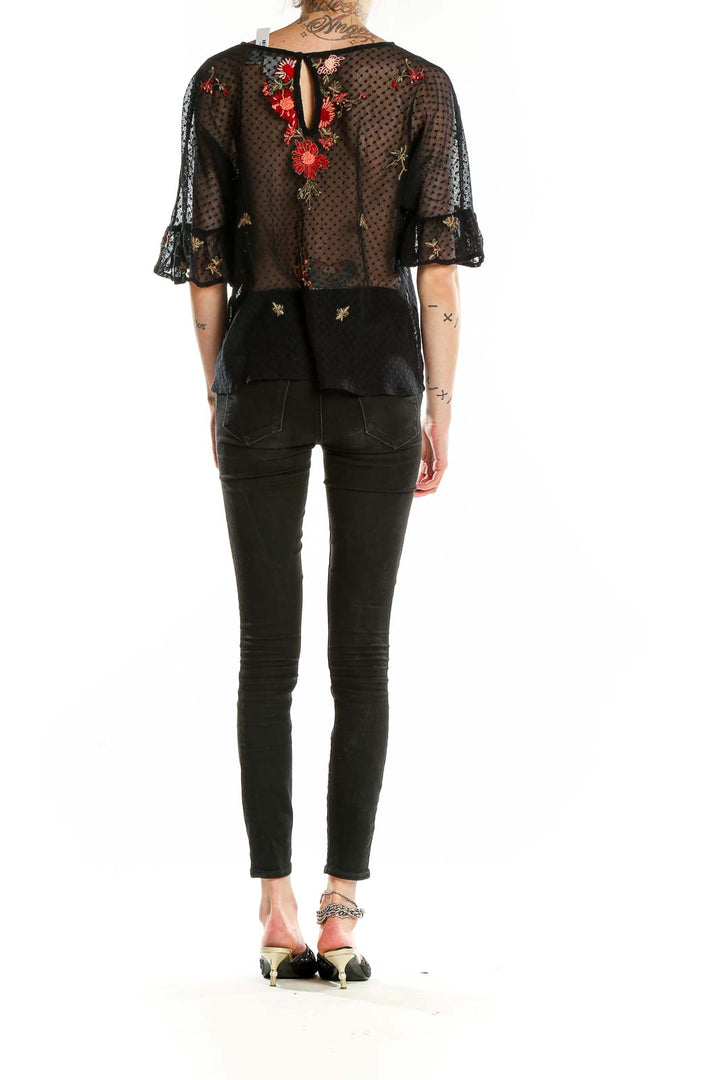 Back view of Maeve black sheer blouse showing keyhole closure and embroidery details