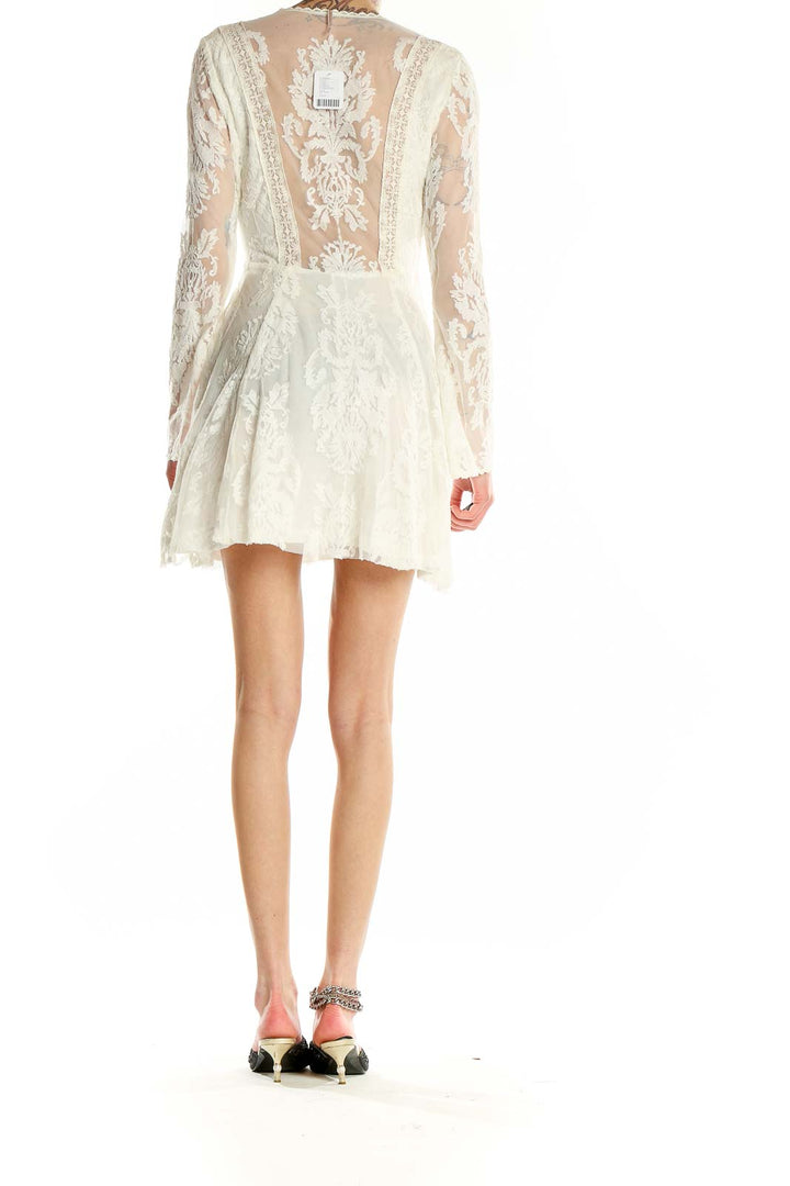 Back view of white lace mini dress showing sheer floral lace pattern