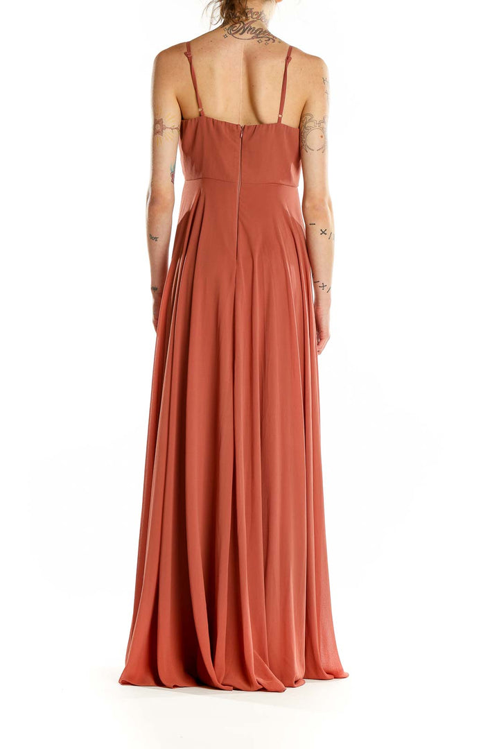 Back view of terracotta pleated maxi dress showing zipper closure and flowing skirt