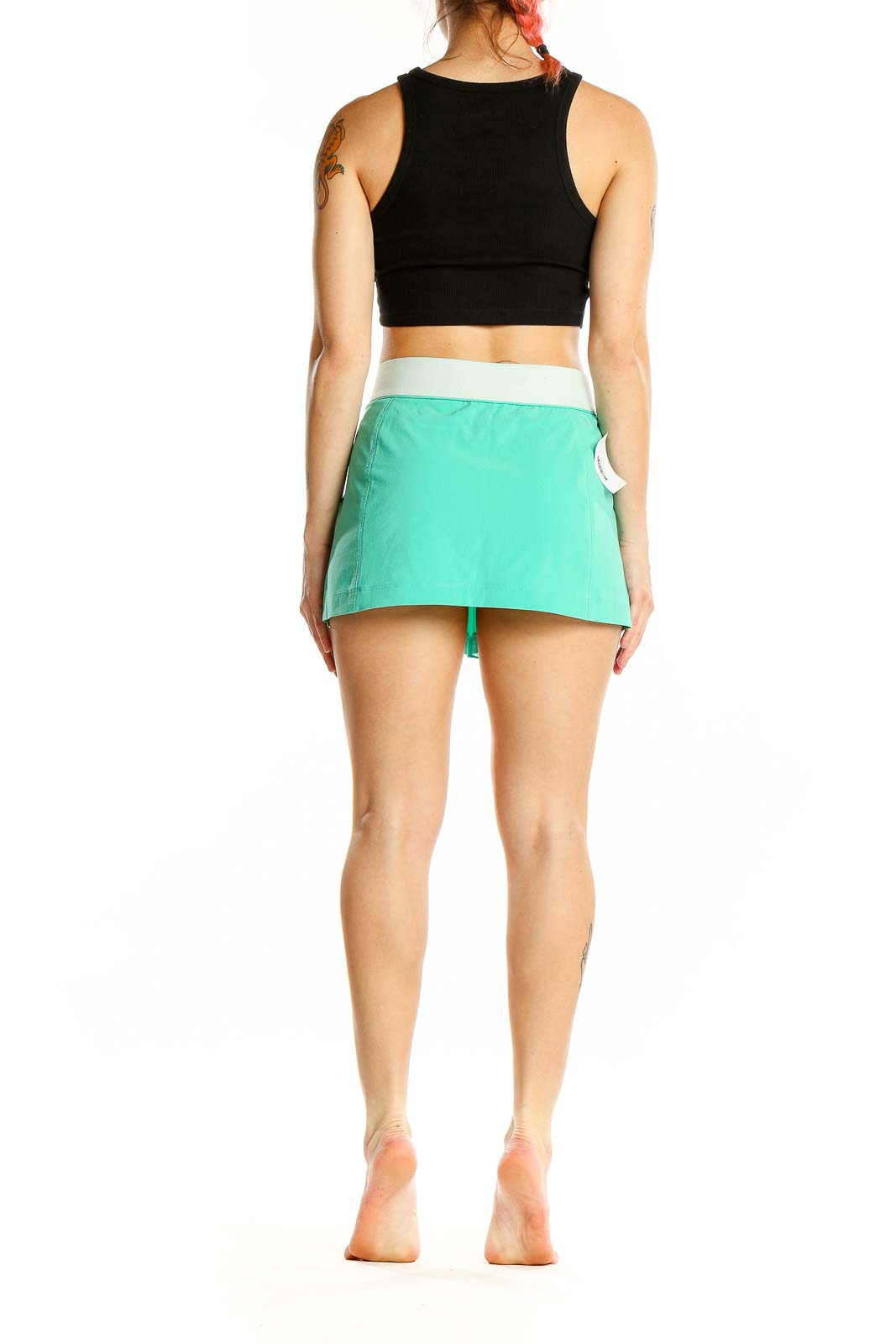 Back view of mint green Nike athletic mini skirt on model