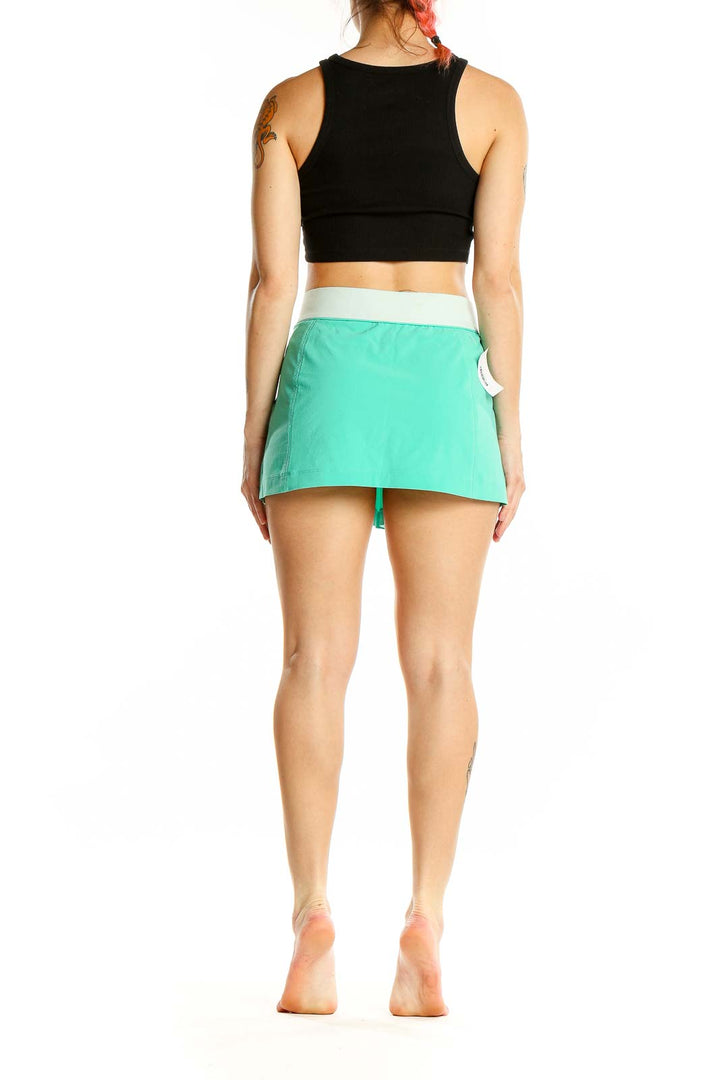 Back view of mint green Nike athletic mini skirt on model