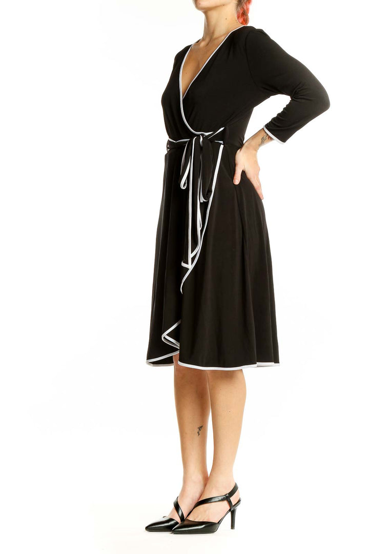 Front view of Calvin Klein black wrap dress with white trim and adjustable waist tie