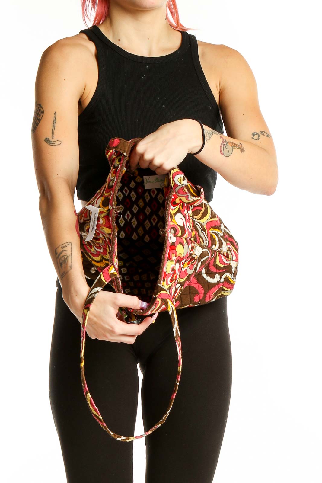 Person holding open Vera Bradley brown floral quilted tote bag showing interior