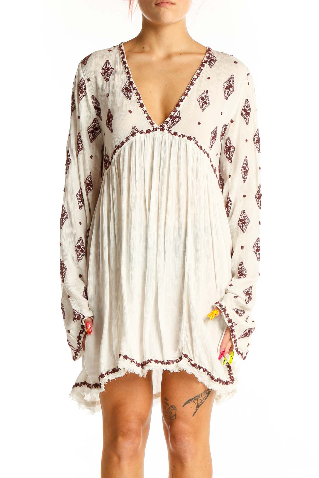 Front view of white Free People boho mini dress with burgundy print and tassel details