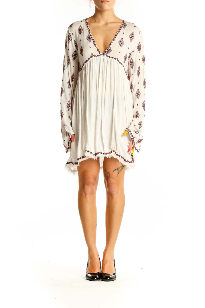 Front view of white Free People boho mini dress with burgundy print and tassel details