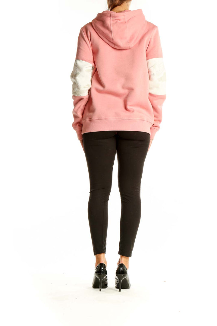 Back view of pink and white Under Armour color block hoodie on model