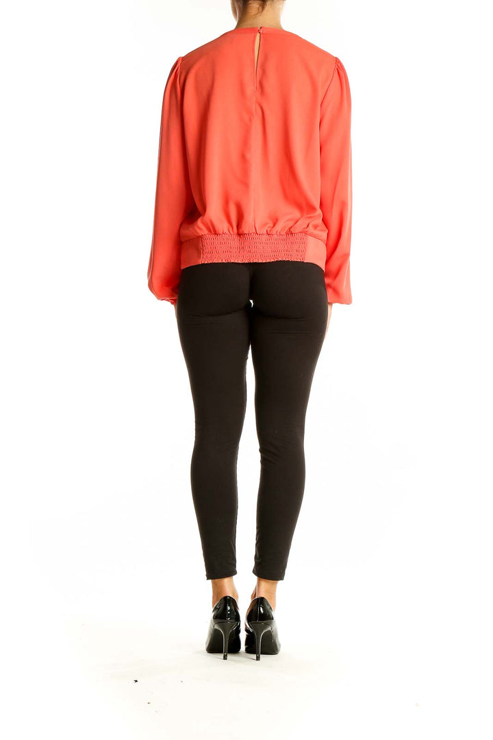 Back view of coral long sleeve blouse with smocked hem by Nine West