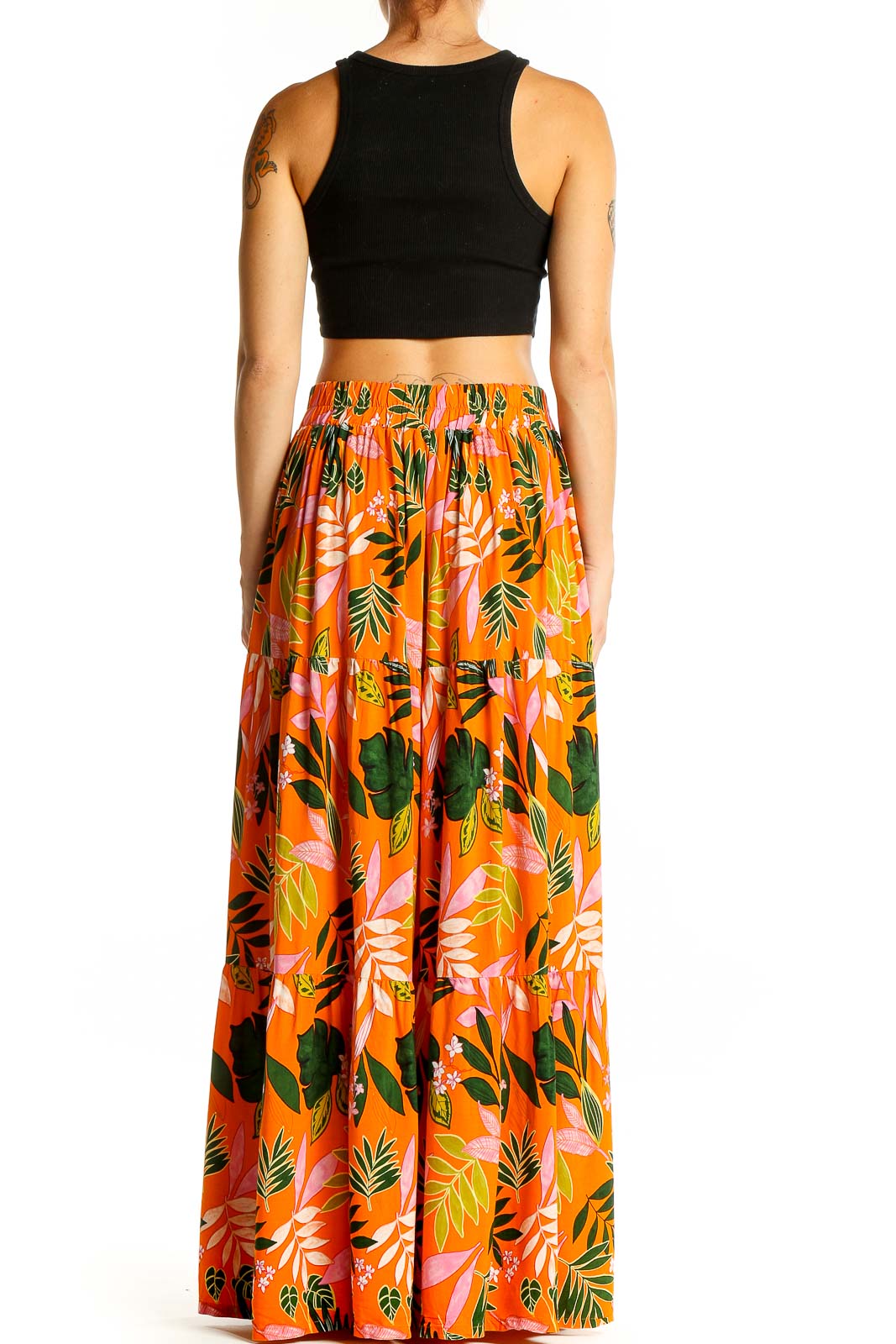 Back view of model wearing Eloquii orange tropical print maxi skirt and black crop top