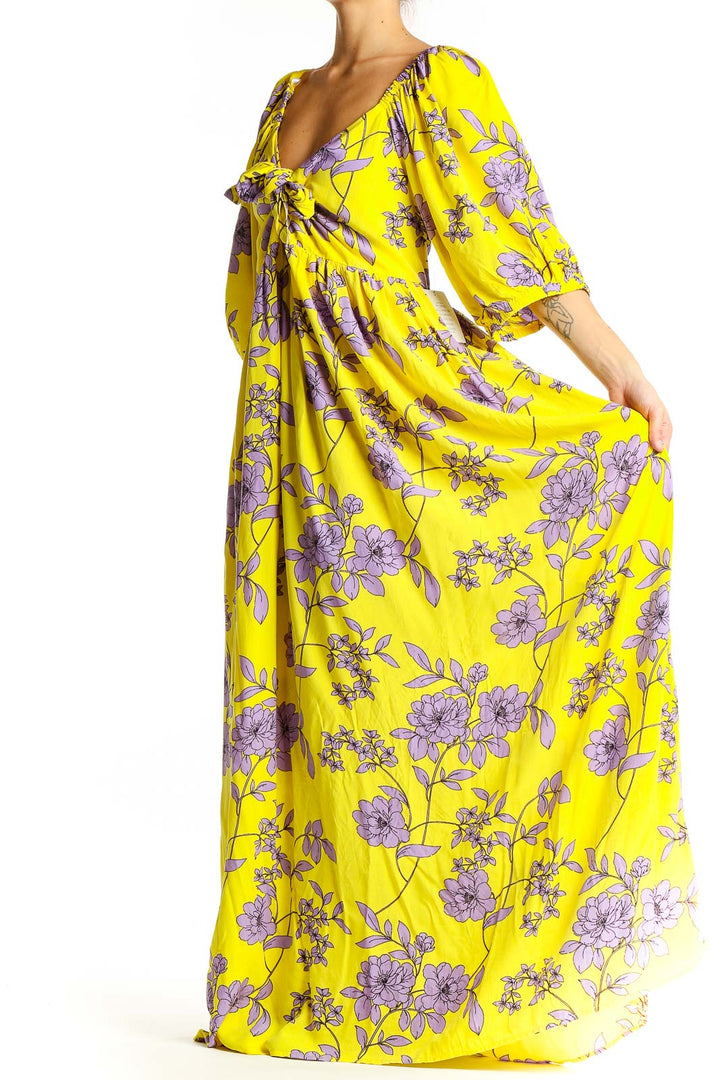 Front view of yellow floral maxi dress with V-neck and tie detail