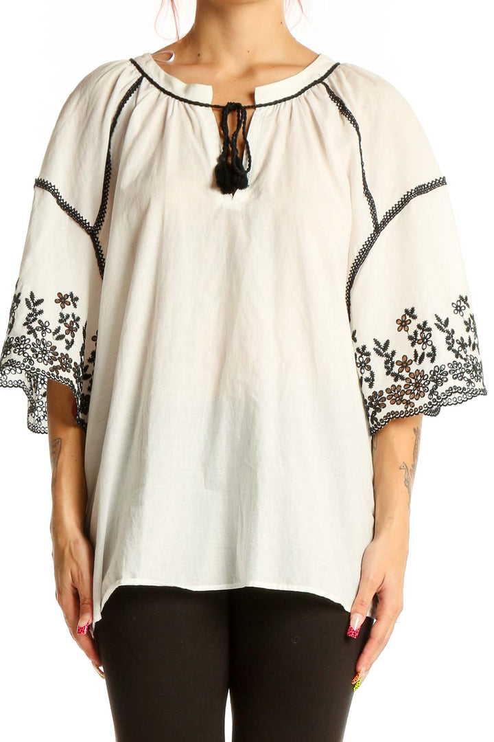 Front view of Zara white cotton peasant top with black embroidery and tassel tie