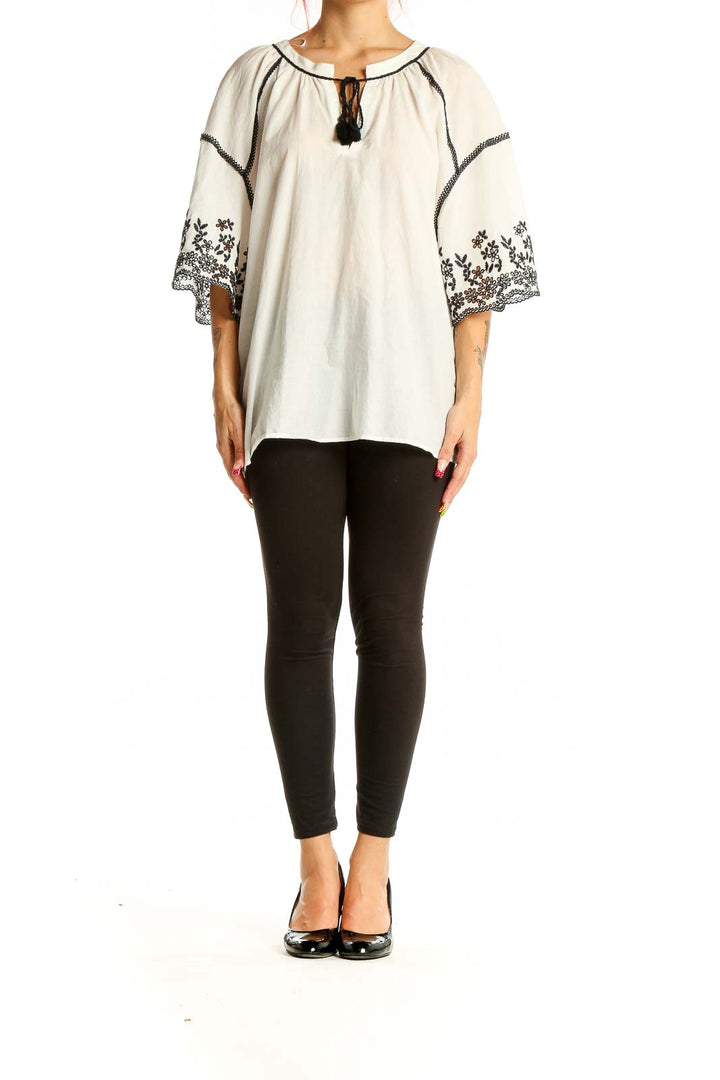 Front view of Zara white cotton peasant top with black embroidery and tassel tie