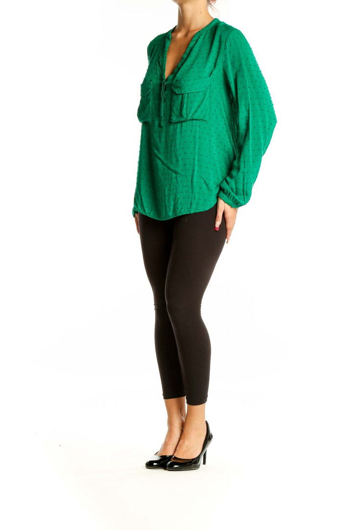 Front view of green dotted rayon blouse with V-neck and front pockets