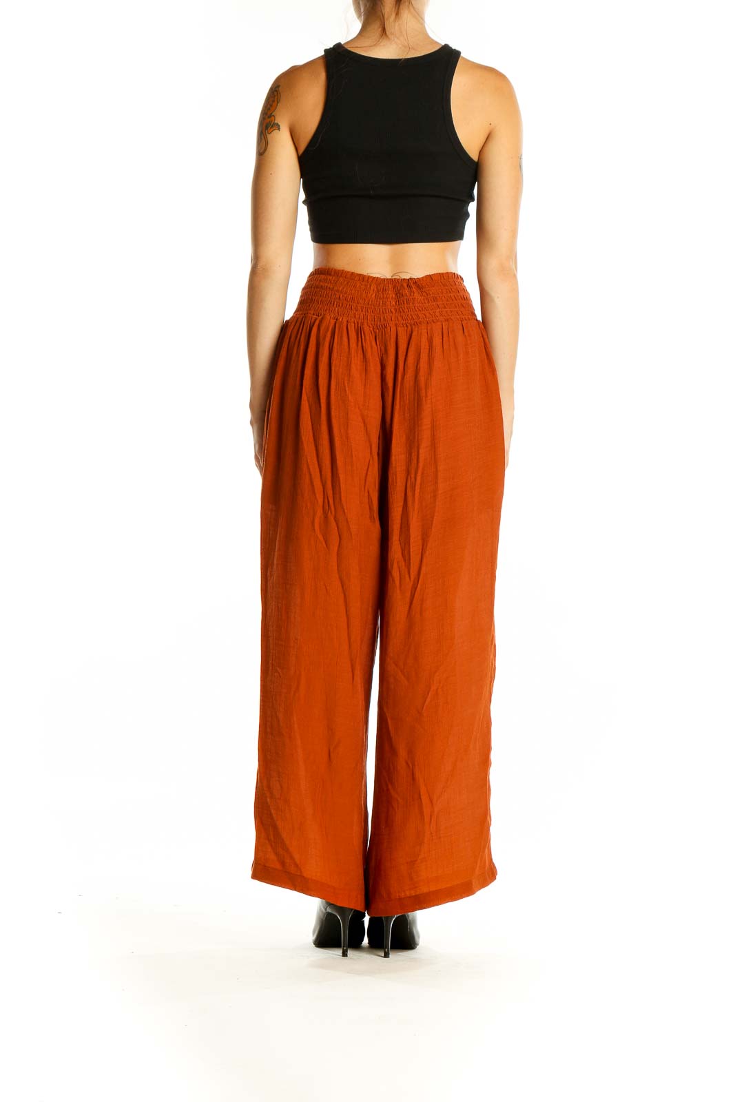 Back view of model wearing Nanette Lepore rust-colored wide-leg palazzo pants with black crop top