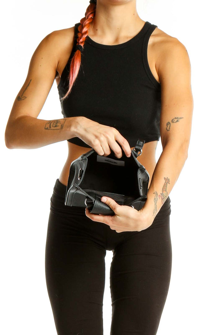 Woman holding open black Nine West mini crossbody bag showing interior