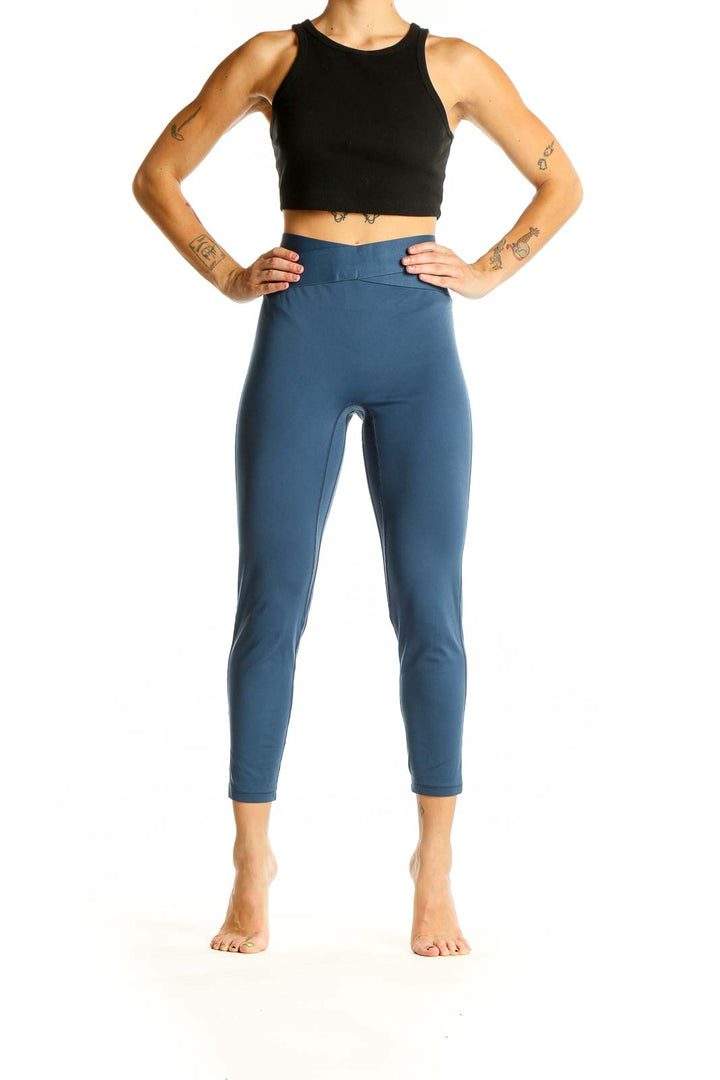 Full body view of woman wearing blue high-waisted cropped activewear leggings with black crop top