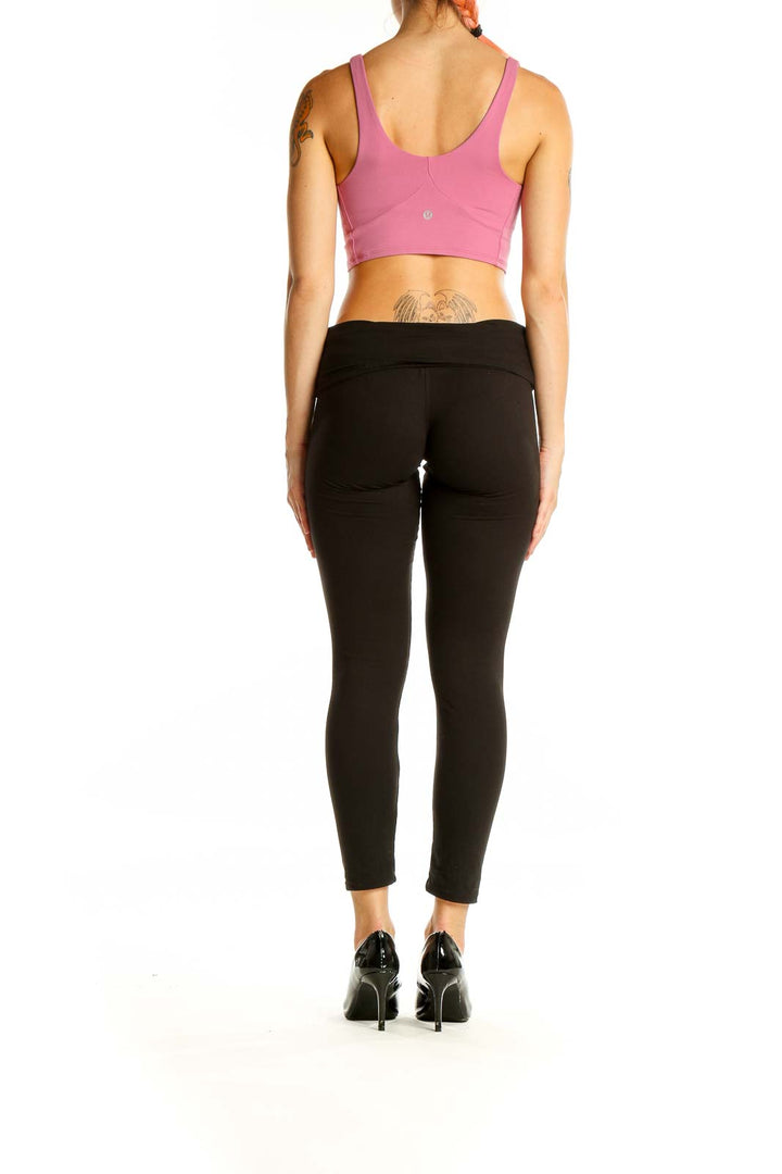 Back view of pink Lululemon crop top on model with black leggings