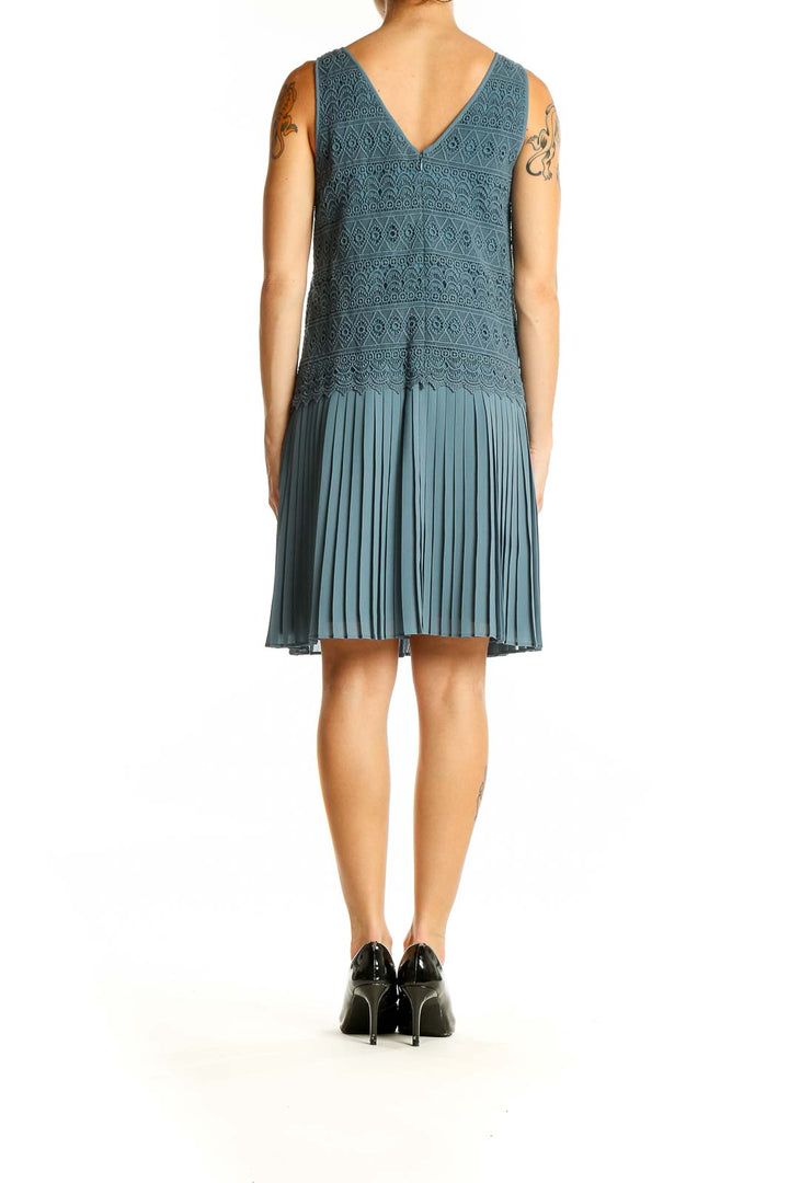 Back view of teal cocktail dress showing V-neck and pleated skirt