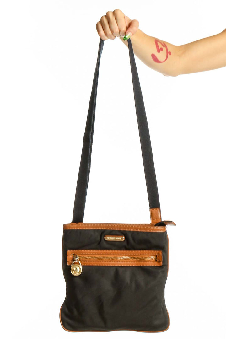 Front view of Michael Kors black leather crossbody bag with brown trim