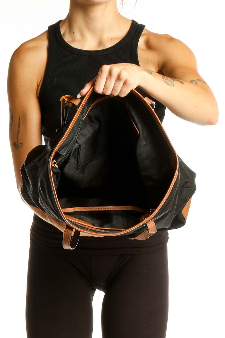 Model holding open Michael Kors black leather tote bag showing spacious interior