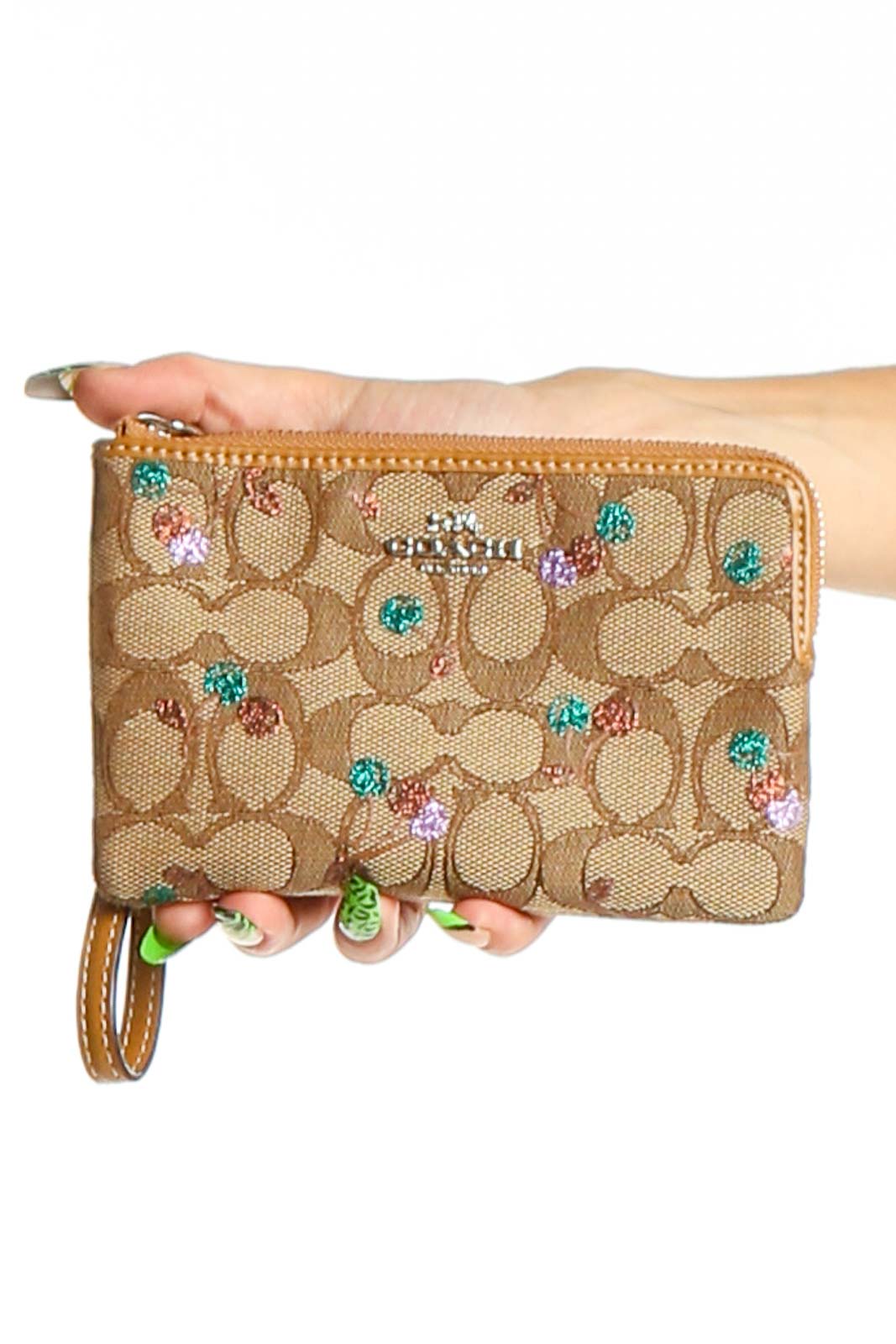 Front view of Coach tan signature canvas wristlet with colorful glitter accents