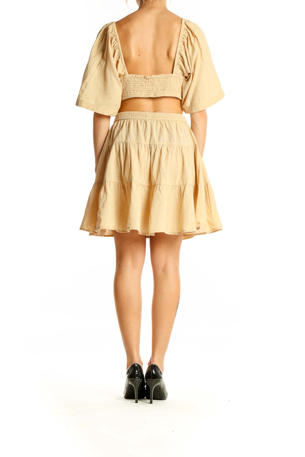 Back view of beige Free People mini dress showing tiered skirt and smocked back