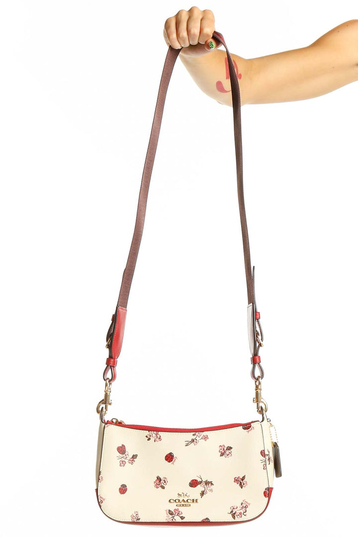 Front view of Coach cream crossbody bag with ladybug and floral print