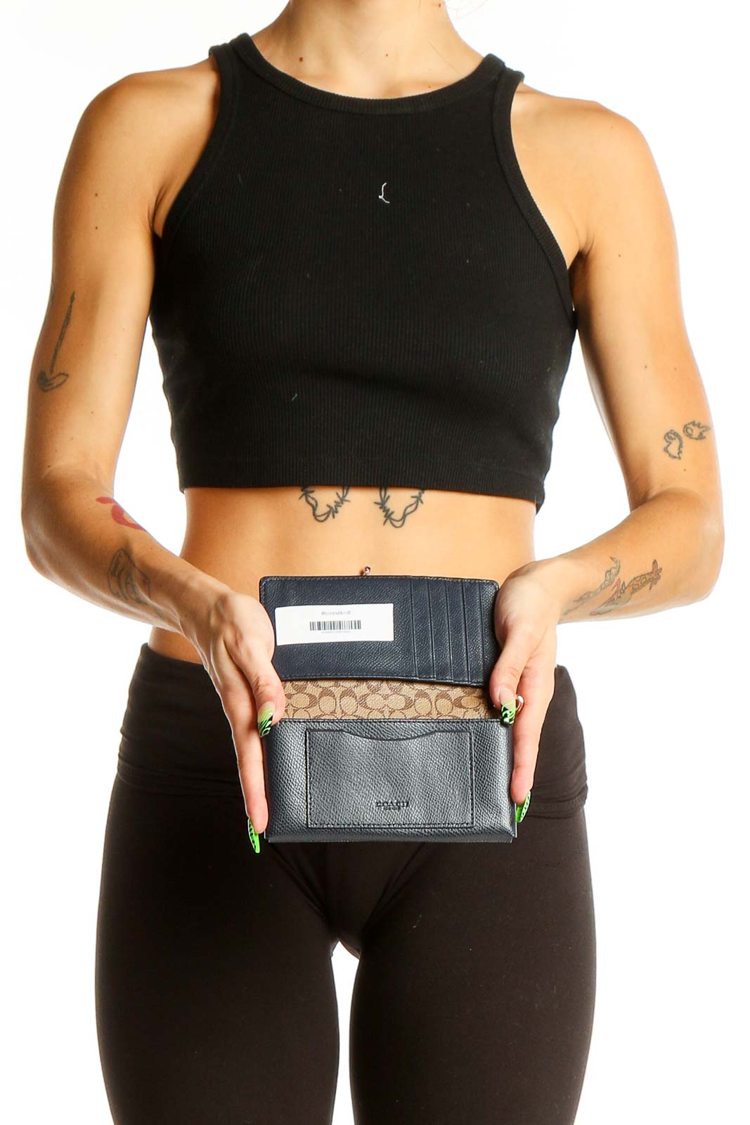 Woman holding black Coach clutch wallet, showcasing its compact size