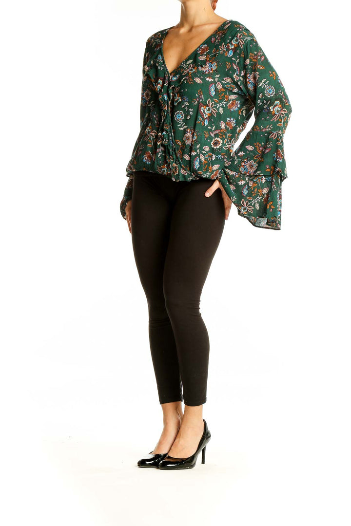 Front view of Chelsea & Violet green floral wrap top with bell sleeves