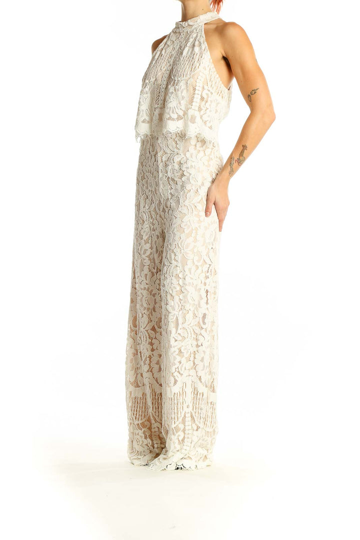 Front view of Lulu's ivory lace halter neck jumpsuit with fringe details