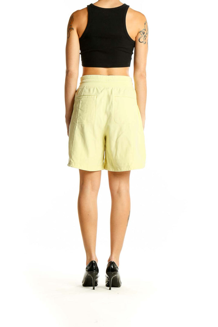 Side view of yellow Callaway shorts on model with black top