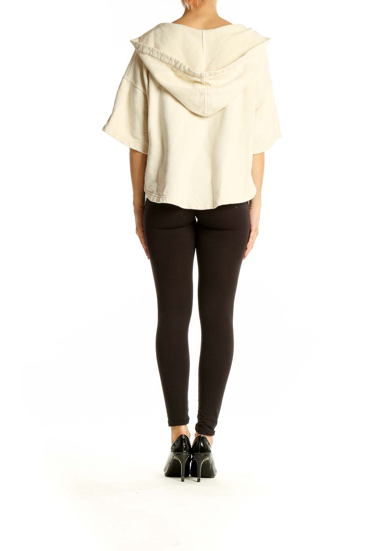 Back view of Joie cream cropped hooded knit top on model with black pants