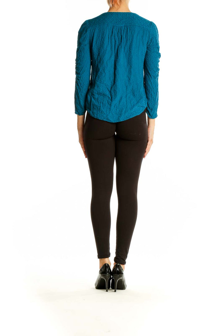 Back view of teal Maeve blouse showing gathered sleeves and curved hemline