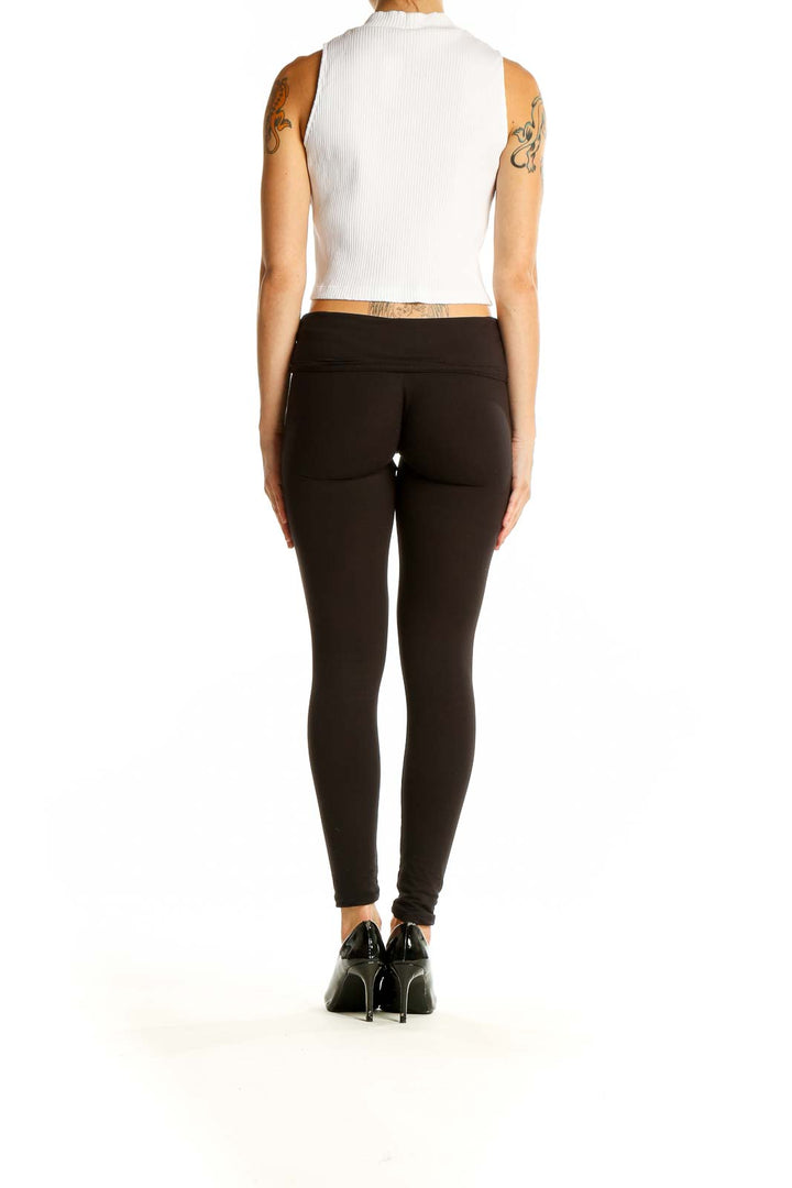 Side view of Uniqlo white ribbed crop tank top on model with black pants