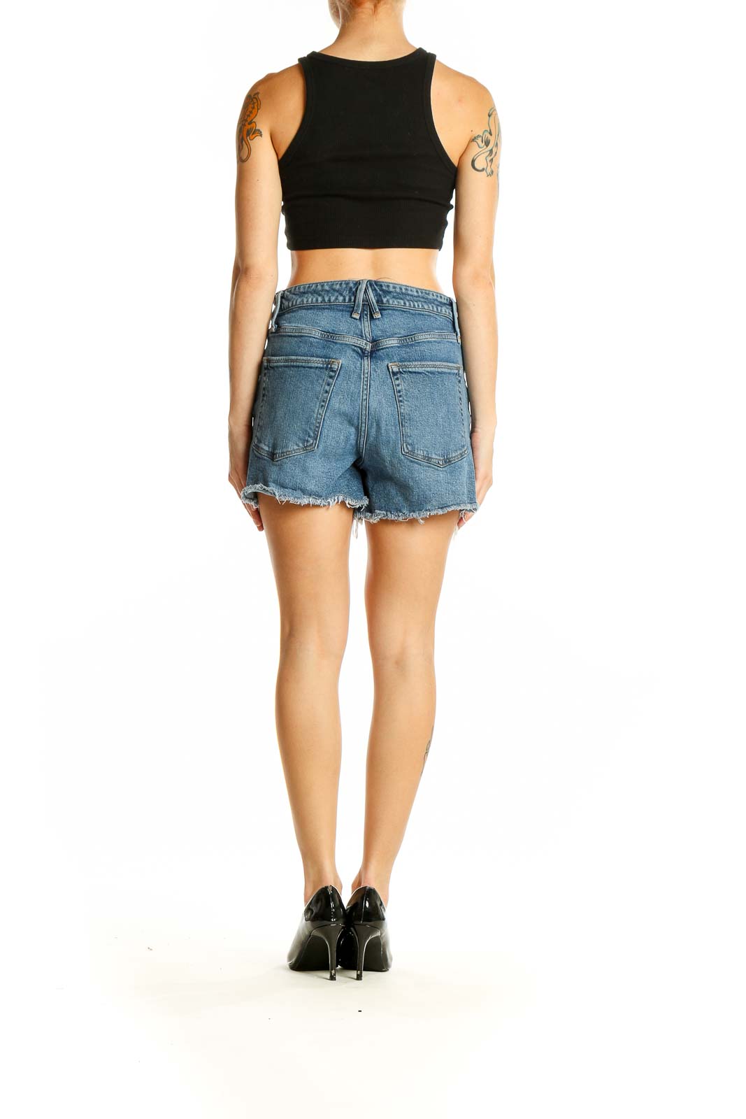 Side view of model wearing Good American blue denim cutoff shorts with black crop top