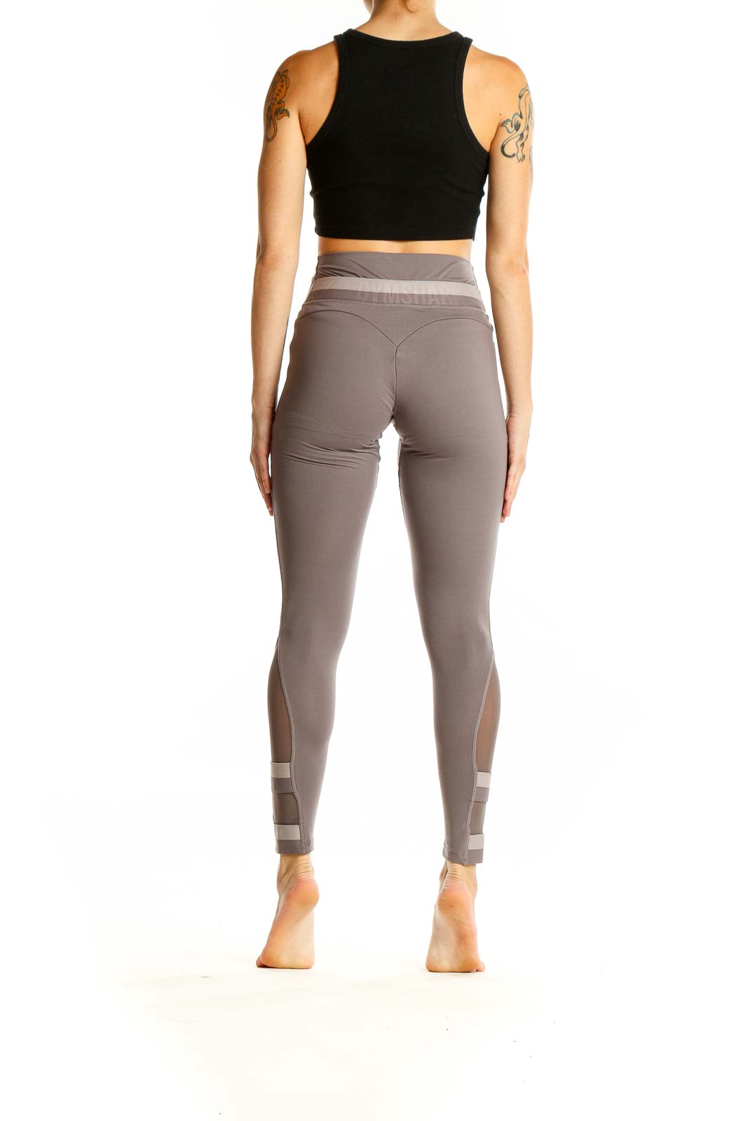 Side view of woman wearing Gymshark taupe high-waisted leggings and black crop top