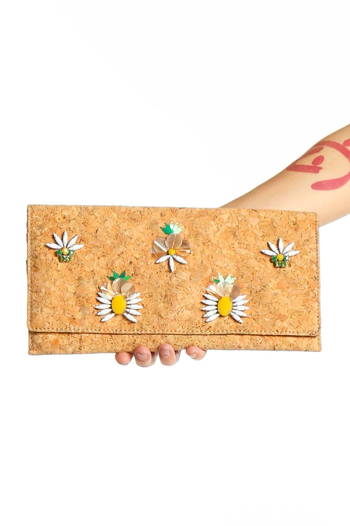 Cork clutch with colorful floral embellishments held in hand