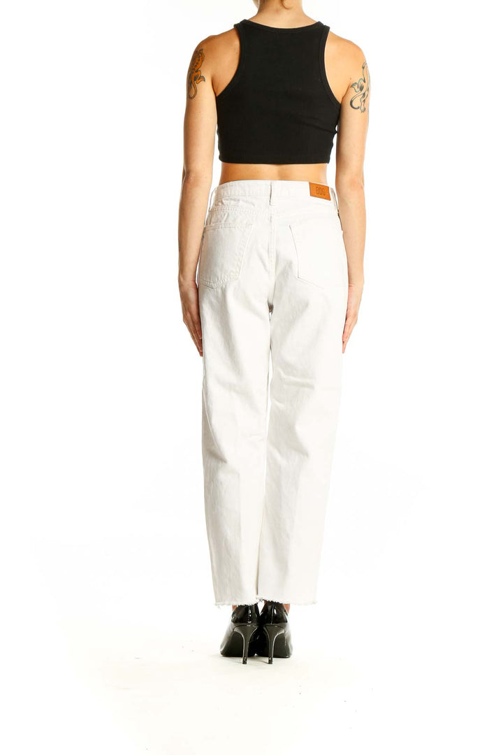 Side view of woman wearing BDG white high-waisted straight-leg jeans with black crop top