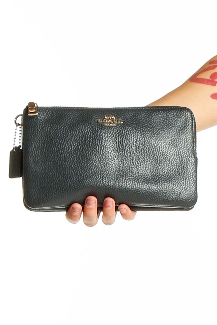 Front view of black leather Coach wristlet clutch with gold-tone logo