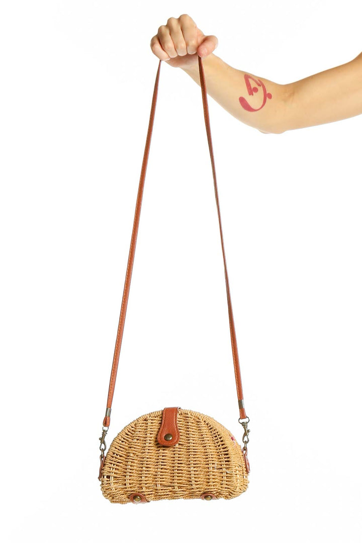 Front view of tan woven rattan half-moon crossbody bag with leather strap