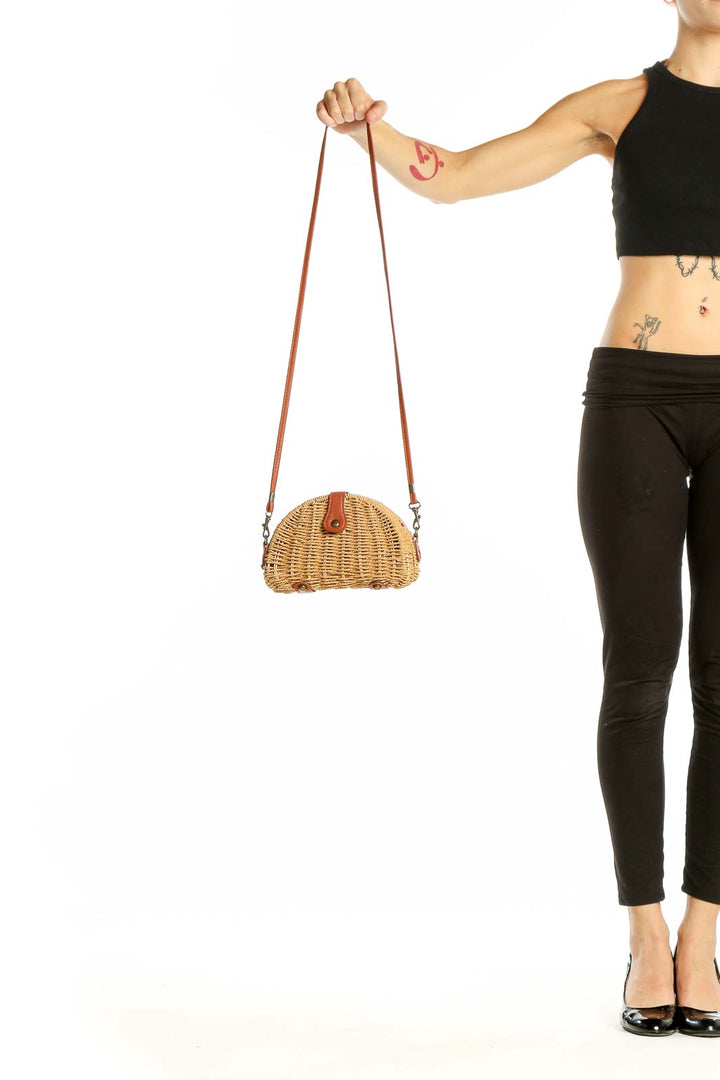 Front view of tan woven rattan half-moon crossbody bag with leather strap