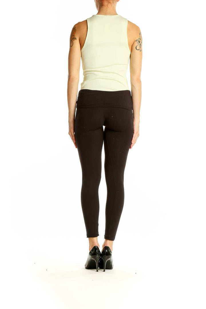 Side view of pale yellow ribbed sleeveless tank top from Express with black leggings